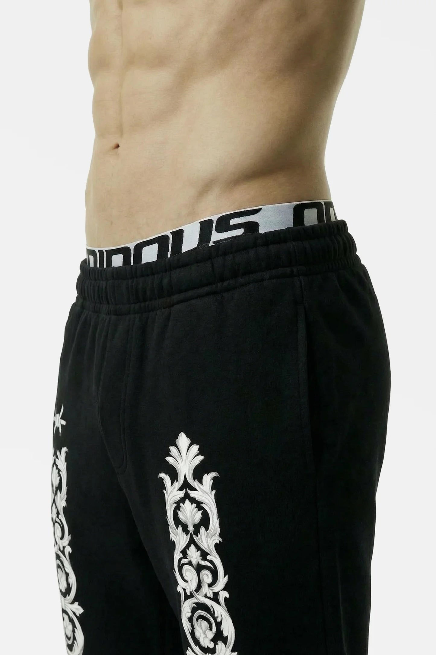 Black athletic pants with white patterns and a visible brand logo on a plain background