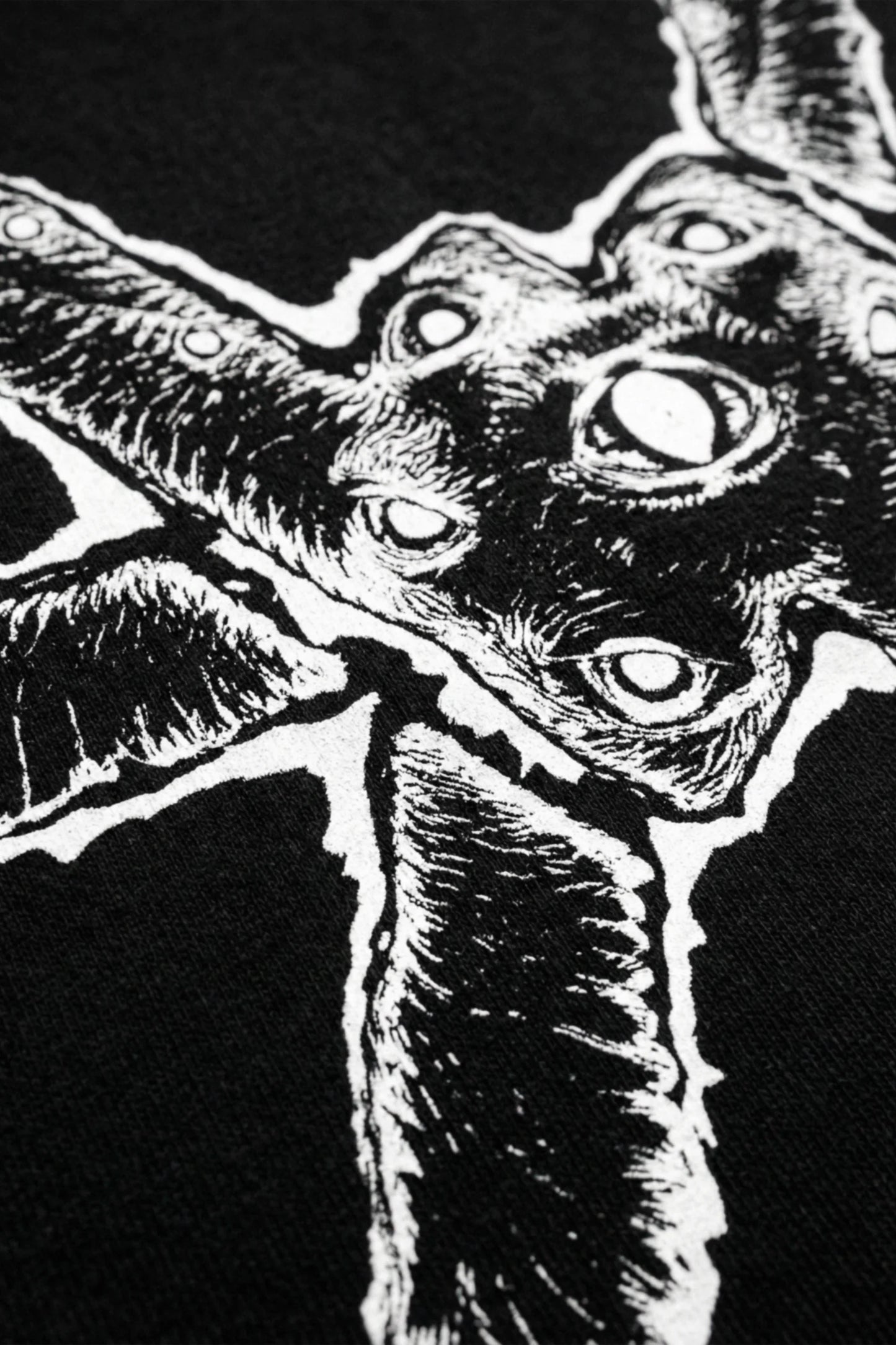 Close up of a black oversized heavyweight t-shirt with a white ominous graphic on a white background