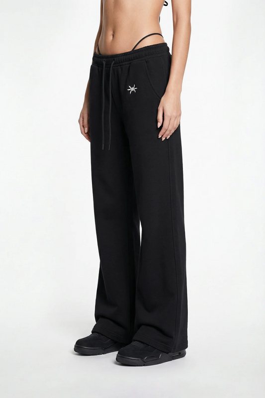 Person wearing black wide-leg pants with a star detail on a white background