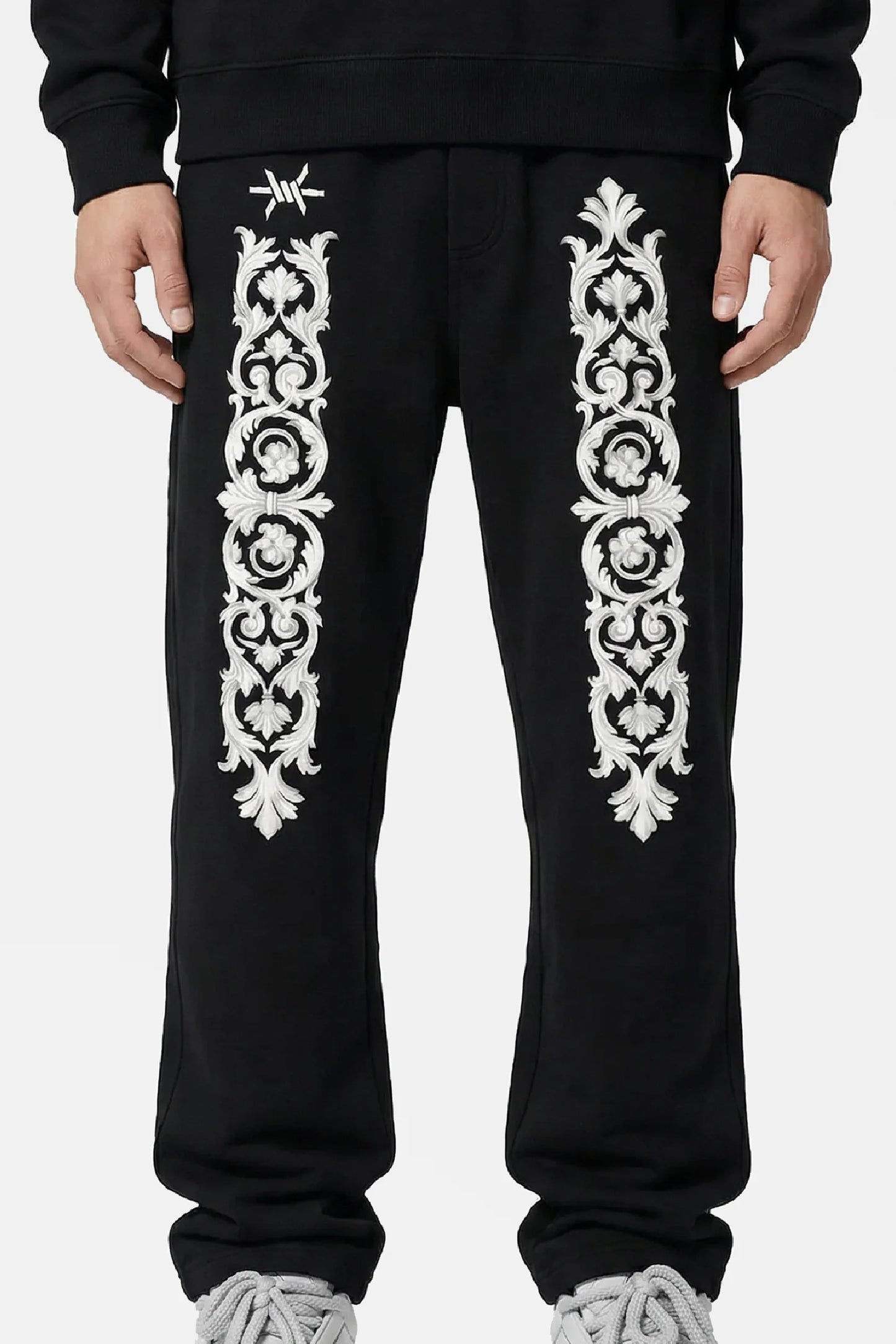Man wearing black sweatpants with white floral baroque patterns and 'Ominous' brand logo on a white background