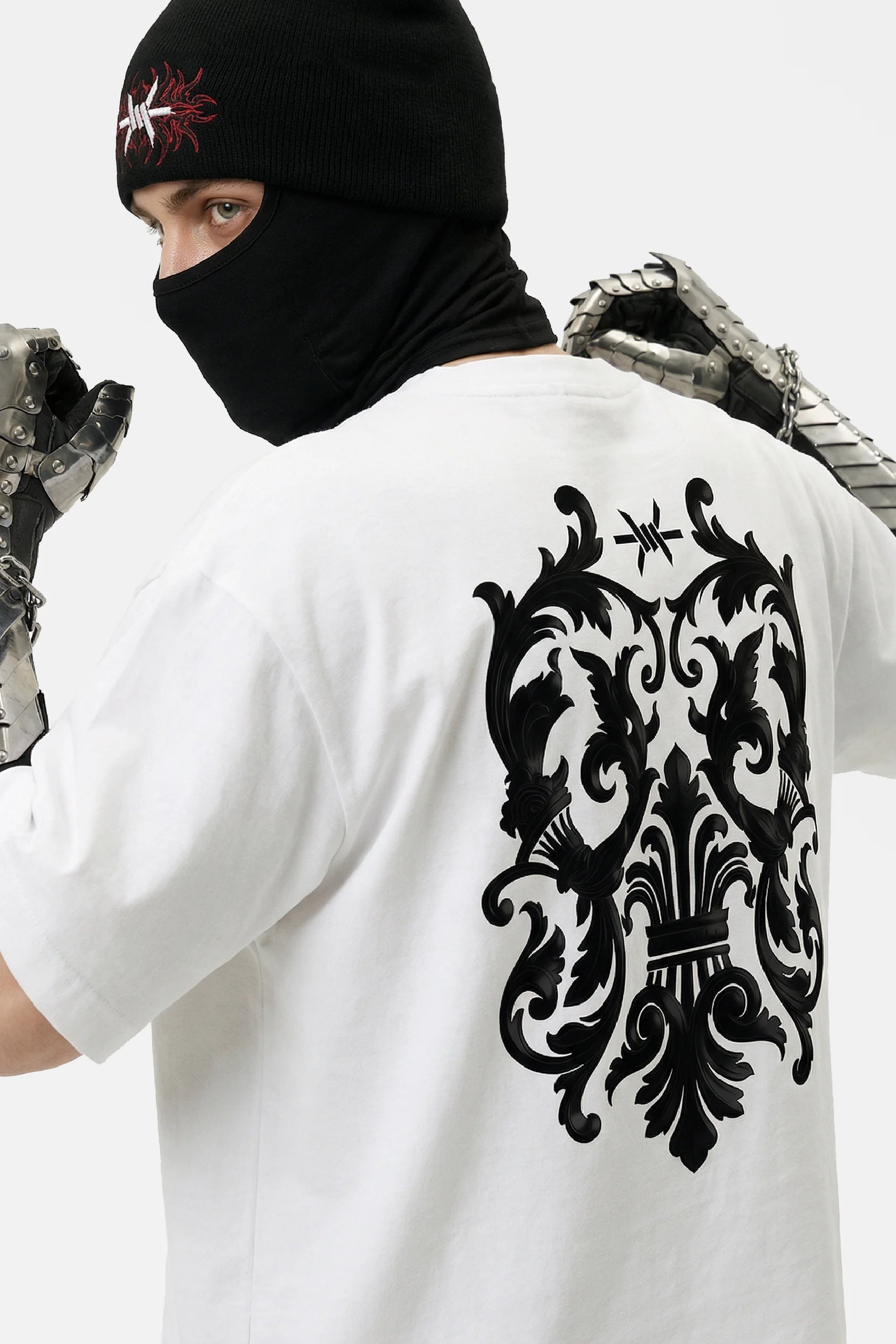 Person wearing a white t-shirt with a black decorative design on the back, standing against a neutral background.