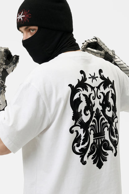 Person wearing a white t-shirt with a black decorative design on the back, standing against a neutral background.