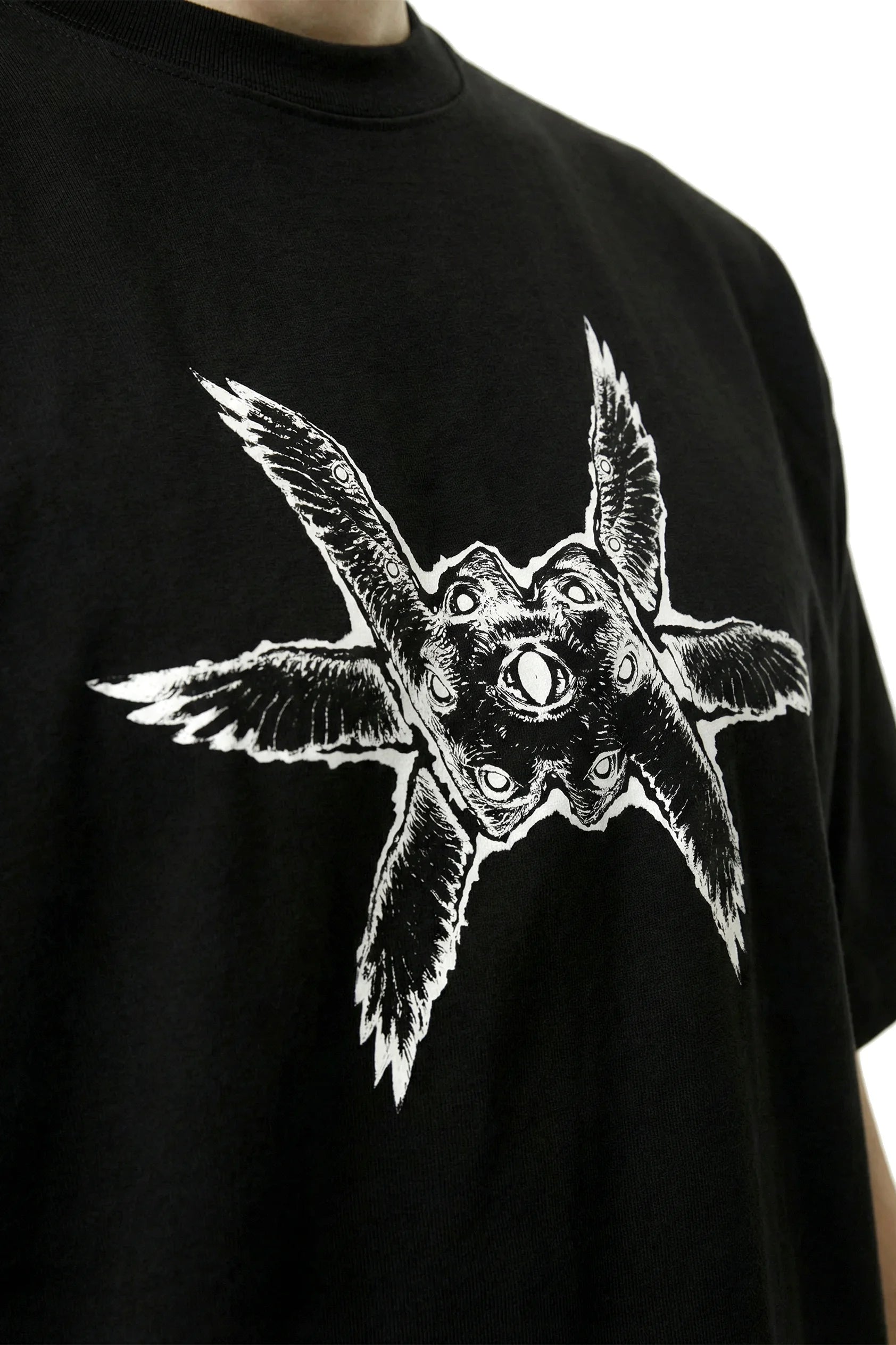 Close up of a black oversized heavyweight t-shirt with a white ominous angel seraph seraphim graphic design on a white background