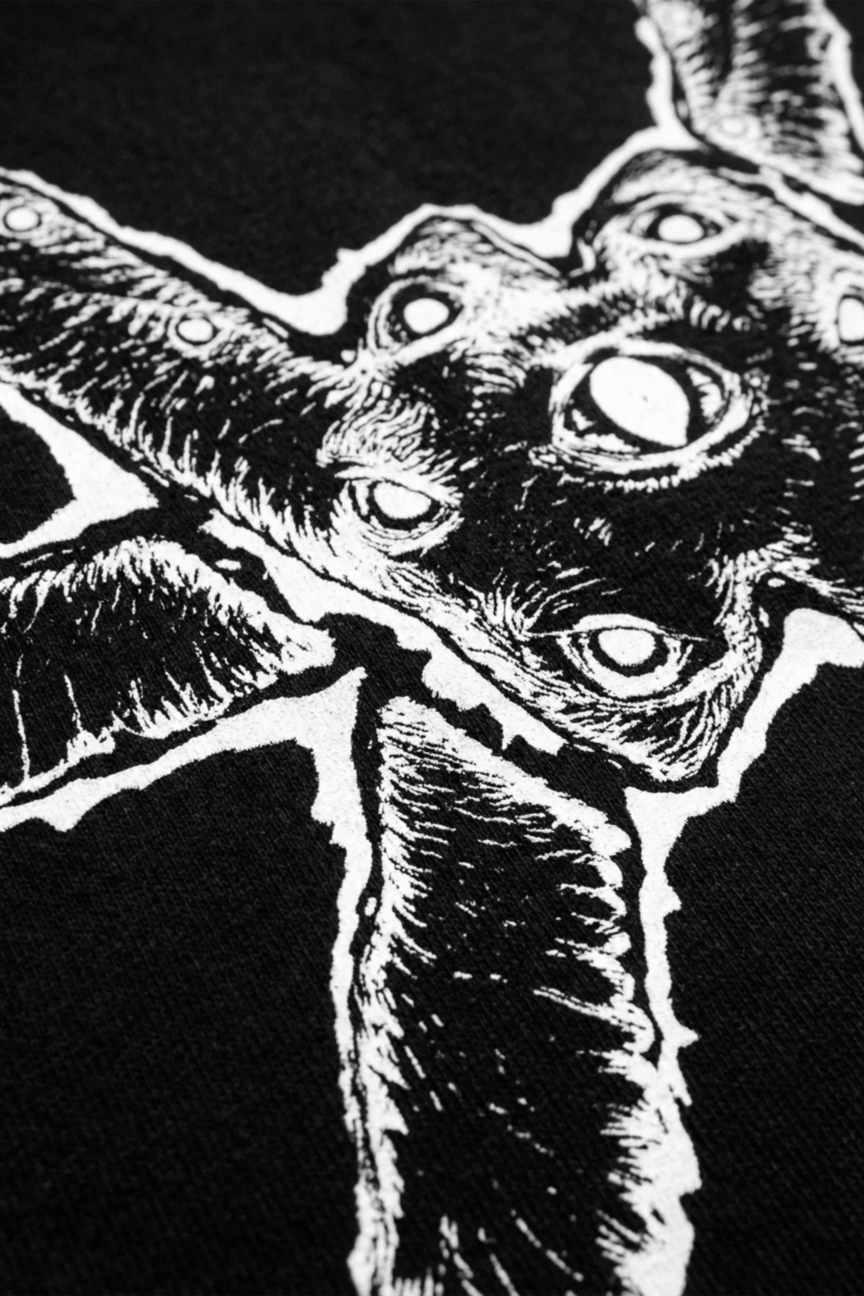 Close up of a black oversized heavyweight t-shirt with a white ominous graphic on a white background