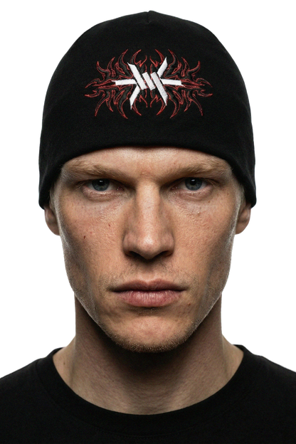 man wearing a black skully skullcap beanie with red and white 'Ominous' logo design on a white background